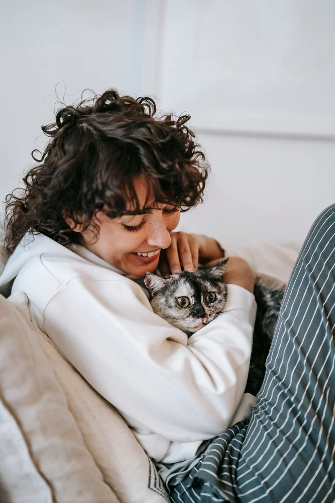 Tutora abraçando seu gato com carinho no sofá de casa